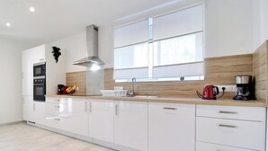 Uma cozinha moderna com armários brancos, um exaustor de aço inoxidável, micro-ondas e máquina de café.
