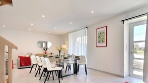Uma área de jantar moderna com uma mesa central, cadeiras e um espelho na parede.
