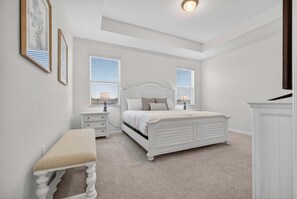 A bedroom with a white bed, bedside tables, a bench, and two windows with blinds. - 2946 BY - Wellness Ridge Sanctuary (Clermont)