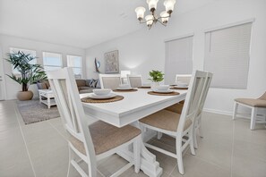 A dining area with a white table, white chairs, and a chandelier. - 2946 BY - Wellness Ridge Sanctuary (Clermont)
