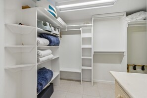 Ein begehbarer Kleiderschrank mit Regalen für gefaltete Kleidung und einer Kleiderstange.