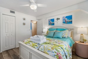 Une chambre à coucher avec un lit, une table de chevet, une lampe et un ventilateur de plafond.