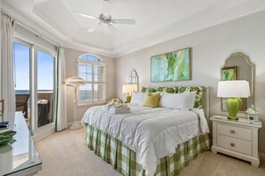 Una camera da letto con un letto, un comodino, una lampada, una ventola a soffitto e vista sull'esterno.