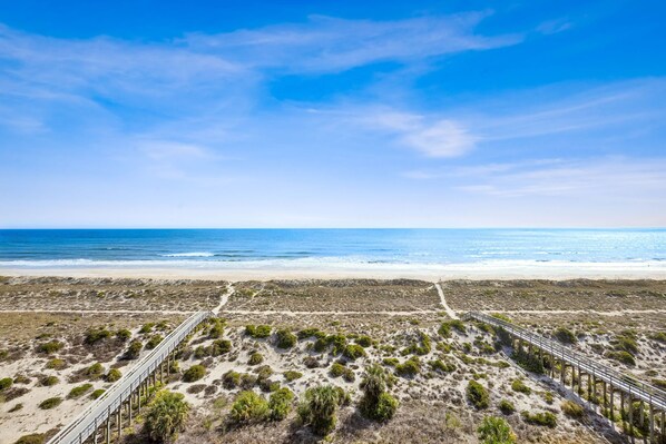 A beach with a wooden boardwalk and sparse vegetation. - Oceanfront Penthouse Retreat – 7th Floor at Ocean Place (Fernandina Beach)