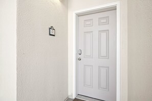 A white door with a keypad lock, a small mailbox, and a textured wall. - Oceanfront Penthouse Retreat – 7th Floor at Ocean Place (Fernandina Beach)