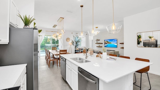 A modern kitchen with a central island, stainless steel appliances, pendant lighting, and a view of the outdoors. - Orlando Resort House: Private Pool & Themed (Kissimmee)