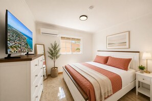 Een slaapkamer met een bed, een televisie, een raam en een plant.