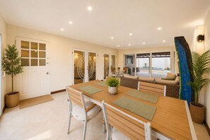Un comedor moderno con una mesa y sillas de madera, una planta en maceta y vistas del patio exterior.