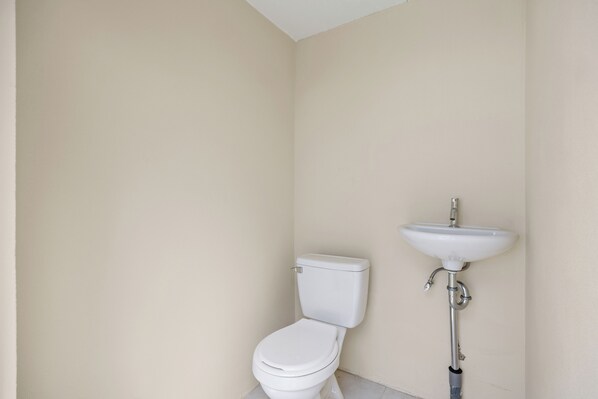 A small, clean bathroom with a toilet and a pedestal sink. - Serenity at Baby Beach (Seroe Colorado)