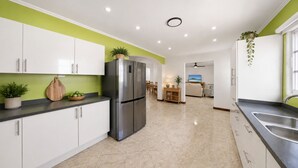 Una cocina moderna con armarios blancos, un refrigerador de acero inoxidable y un comedor con mesa y sillas.
