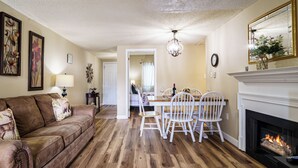 Un salon avec une cheminée, un coin repas et un couloir menant à une autre pièce.