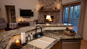 Eine Küche mit Granit-Arbeitsplatten, einer integrierten Spüle und einem Kamin aus Stein.