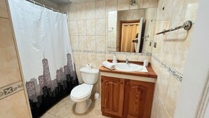 Een badkamer met toilet, wastafel en douchegordijn.