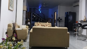 A living room with a sofa, a glass coffee table, a TV, and a staircase leading to another level.