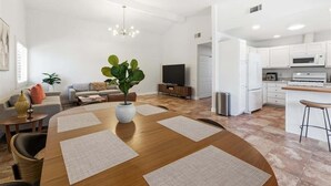 En moderne stue med et træspisebord, en stor plante og en sofa.