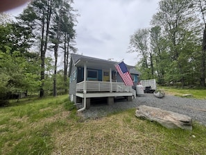 Eine Holzhütte mit Veranda, einer amerikanischen Flagge und einem Grillplatz.