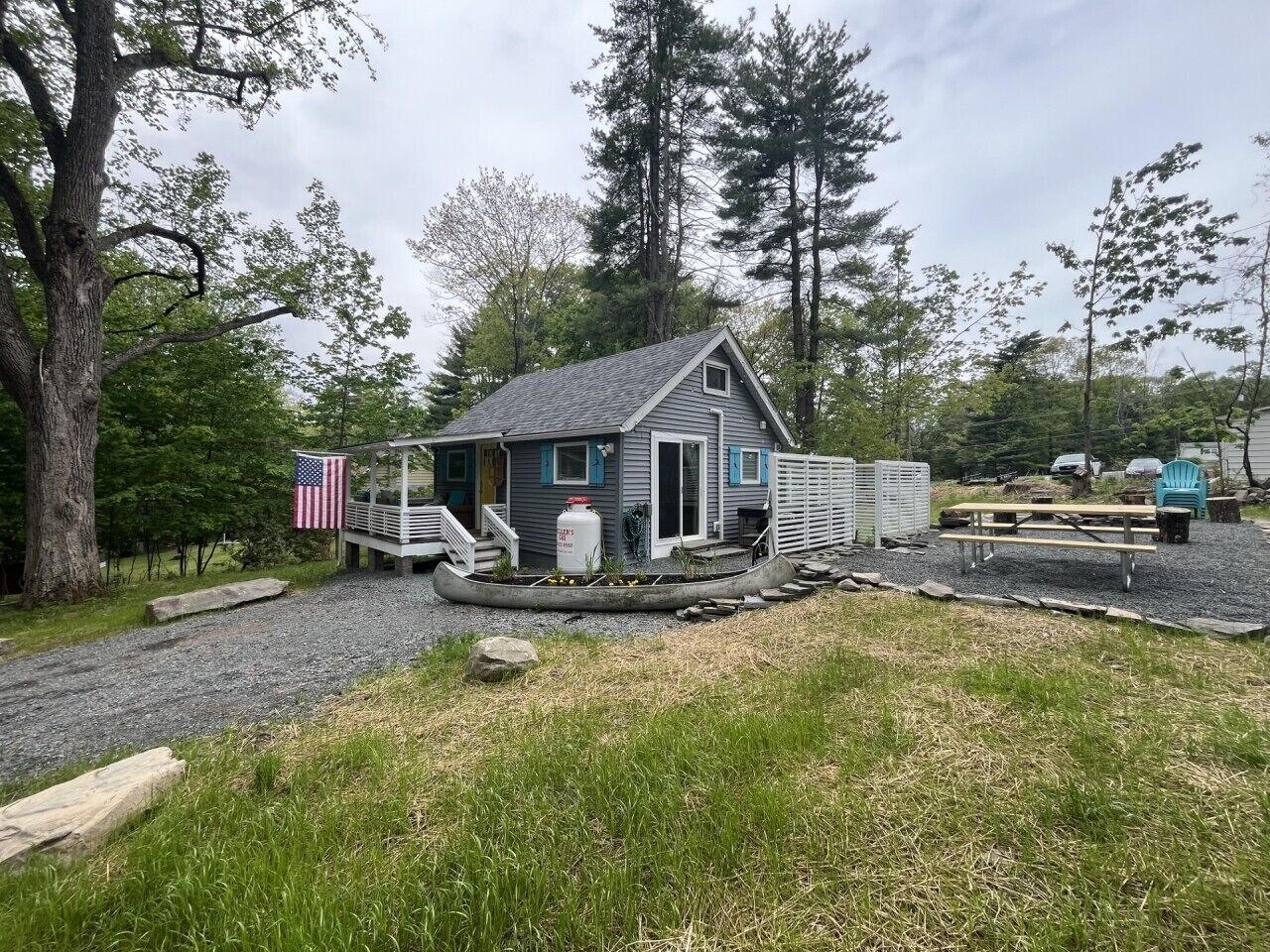 A small cabin with a porch, a flag, and a canoe.