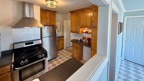 A kitchen with a stove, oven, refrigerator, and wooden cabinets.