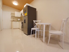 A kitchen with white cabinets, a refrigerator, a microwave, and a white dining table with chairs. - Cozy 1-bedroom townhome in beautiful Panamá with AC (Panamá)