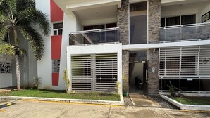 A modern building with a red and white facade, a gated entrance, and a parking area. - Apartment in La Vega, 20 minutes from the Fula river. (Concepcion De La Vega)