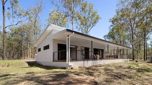 A modern single-story house with a covered porch, surrounded by trees.