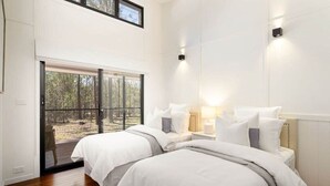 A bedroom with two beds, a large window, and a view of the outdoors.