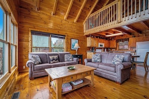 Ein Holzblockhaus-Innenraum mit zwei Sofas, einem Couchtisch und einer Küchenzeile.