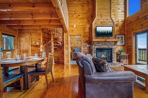 Ein Holzblockhaus mit Essbereich, Kamin und einer Couch.