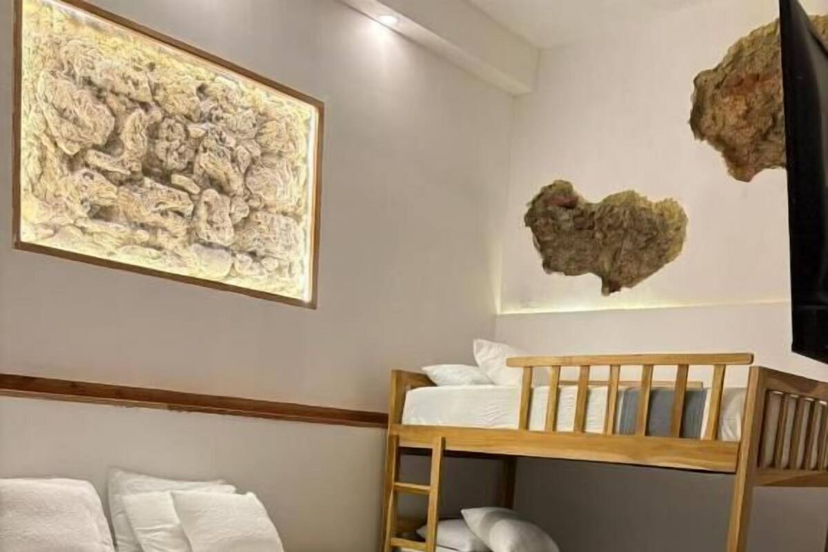 A room with a bunk bed, a desk, a painting, and a rock decoration.