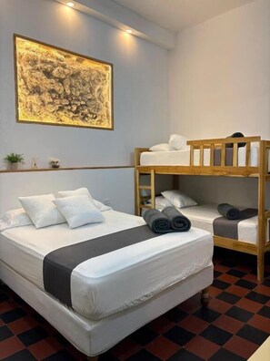 A room with a bunk bed, a single bed, a framed artwork on the wall, and a small plant on a shelf. - Casa Centro Histórico Room (Cartagena)