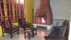 A living room with a brick fireplace, wooden furniture, and a yellow wall.