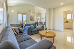A modern living room with a grey sofa, a coffee table, and a dining area in the background. - Villa Lotus 6 with private pool and jacuzzi. (Pula)