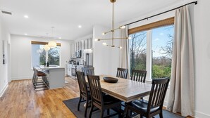 Et moderne køkken med hvide skabe, en central ø og et spiseområde med et træbord og stole.