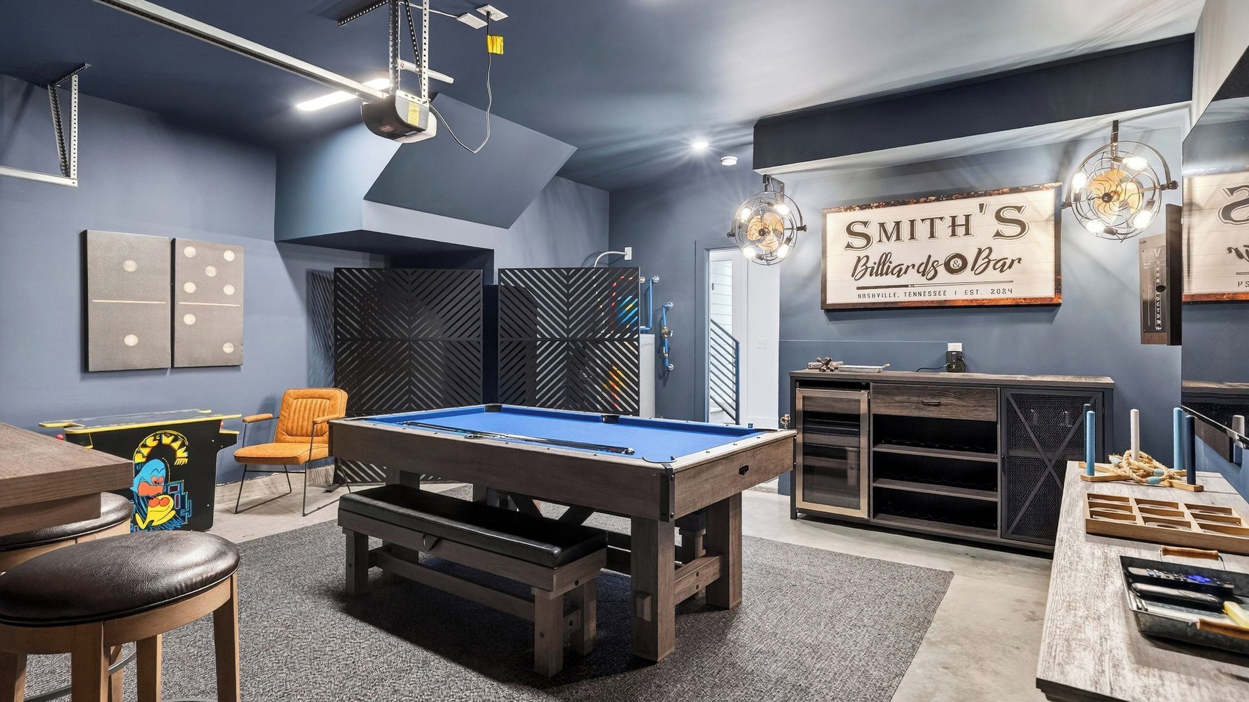 A billiards room with a pool table, chairs, and a billiard cue rack.