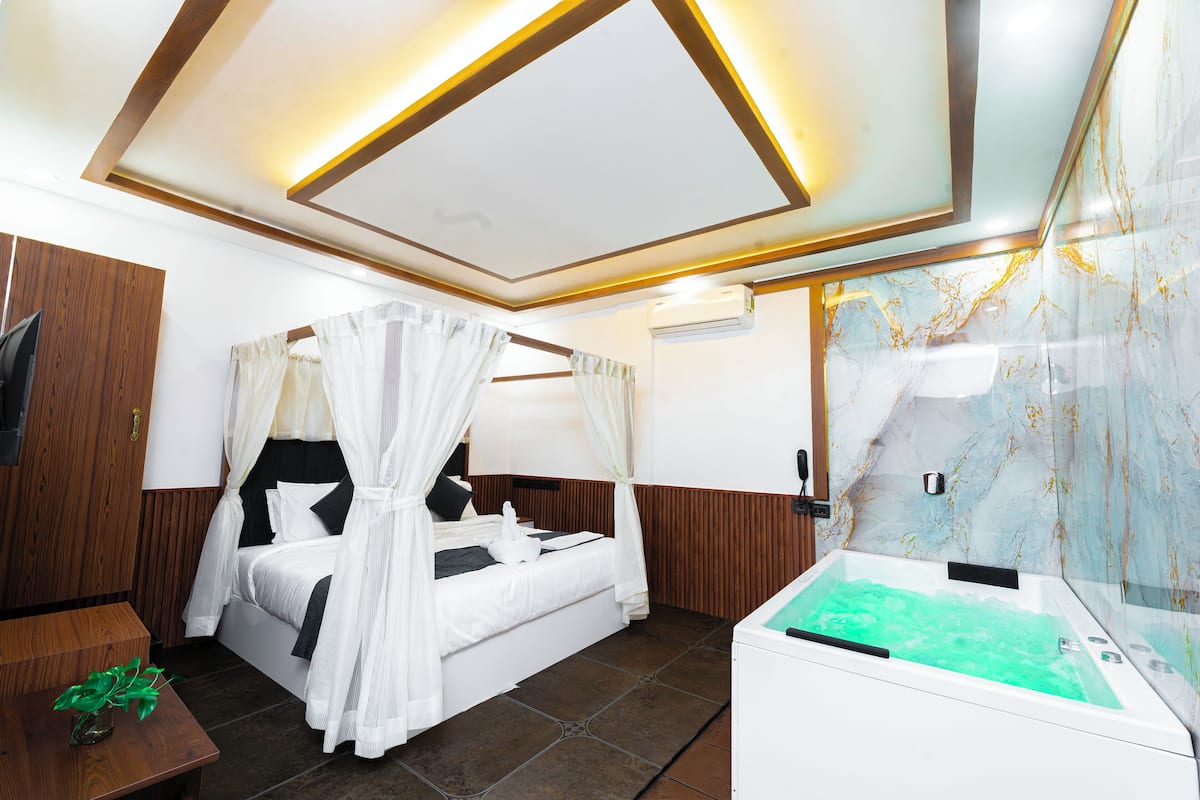 A bedroom with a bed, a TV, a massage chair, and a jacuzzi.