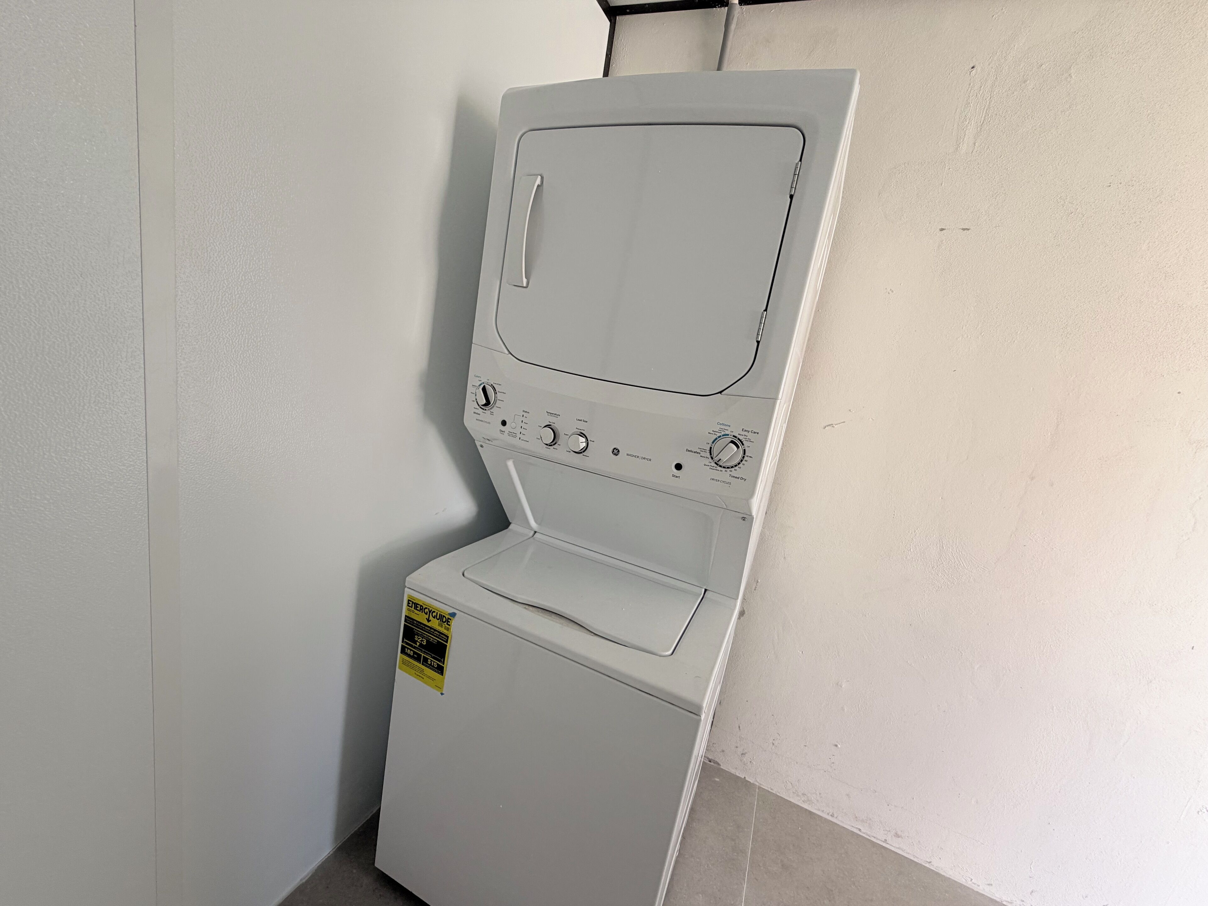 A compact, white front-loading washing machine with a control panel, a front control knob, and a yellow energy efficiency label.