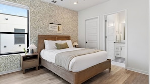 A bedroom with a bed, nightstands, a window, a door, and a wall with a leaf pattern.