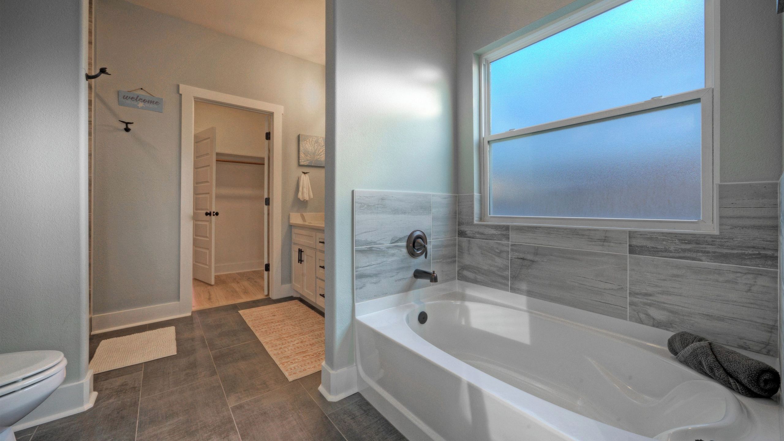 Une salle de bain avec une baignoire, des toilettes, un espace douche et une fenêtre.