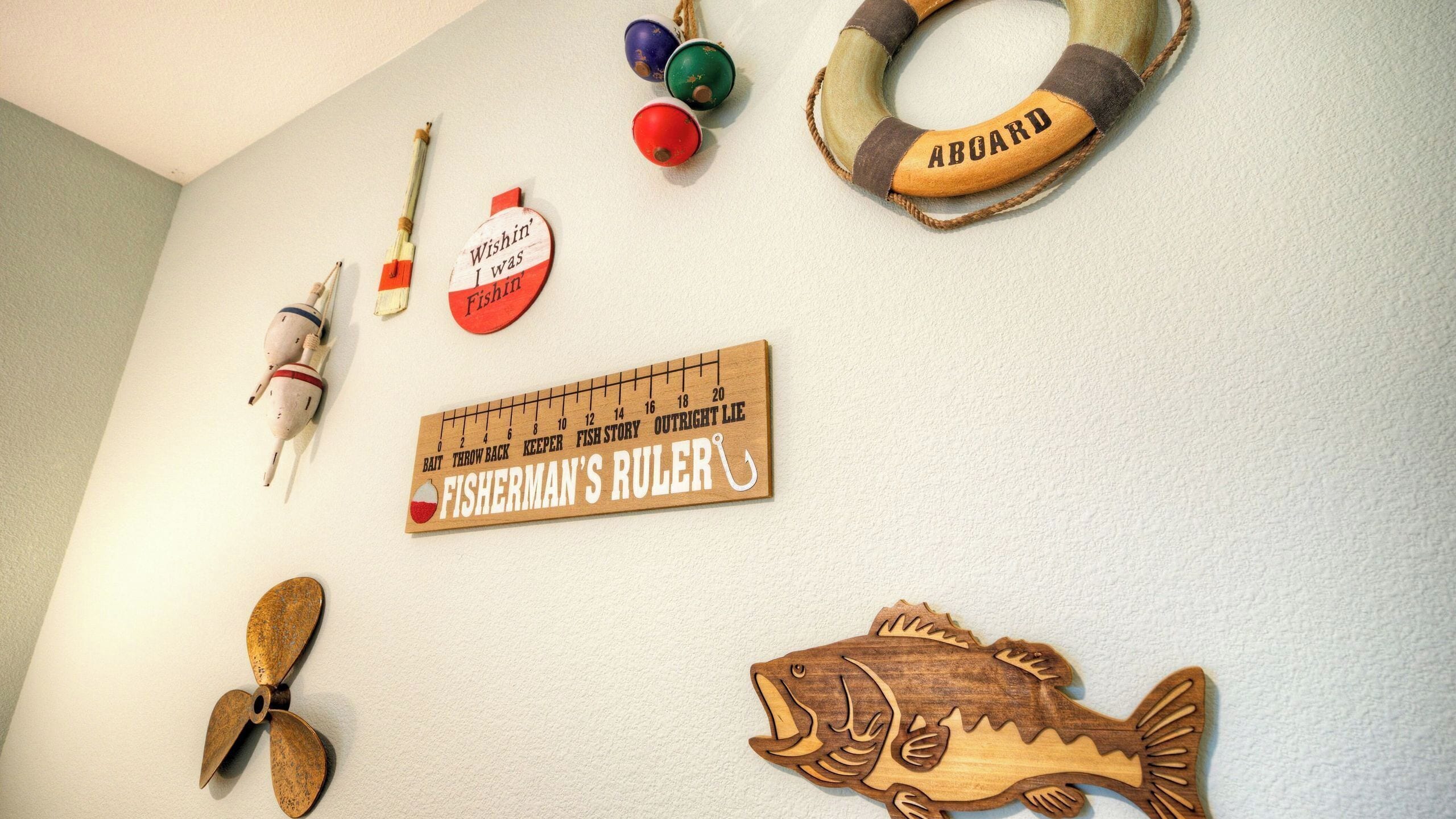 A wall with fishing-themed decorations including a fish, a ruler, and various fishing-related items.