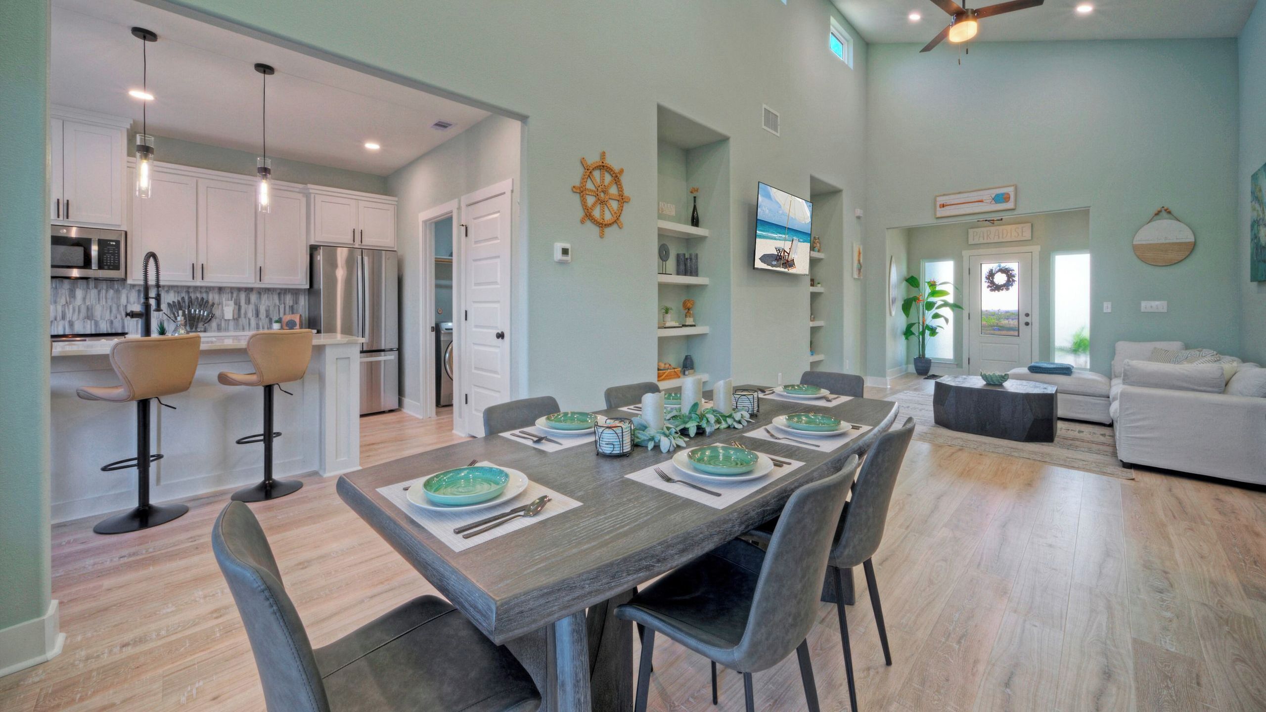 Un amplio salón con una mesa de comedor preparada para cuatro personas, una cocina con electrodomésticos modernos y una zona de estar acogedora con un sofá.