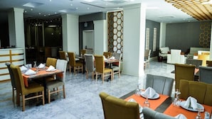 A modern dining area with tables set for two, featuring a mix of wooden and upholstered chairs.