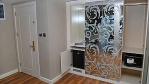 A room with a white door, a wardrobe with a decorative panel, and a small black appliance.
