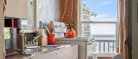 A compact kitchen with wooden cabinets, a built-in oven, and a view of the outdoors through a window.