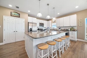A kitchen with a central island, white cabinetry, and bar stools.