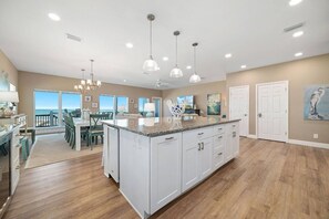 A spacious kitchen with a large island, pendant lighting, and a view to the outside.