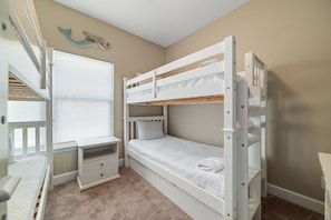 Een slaapkamer met een stapelbed, bureau en raam.