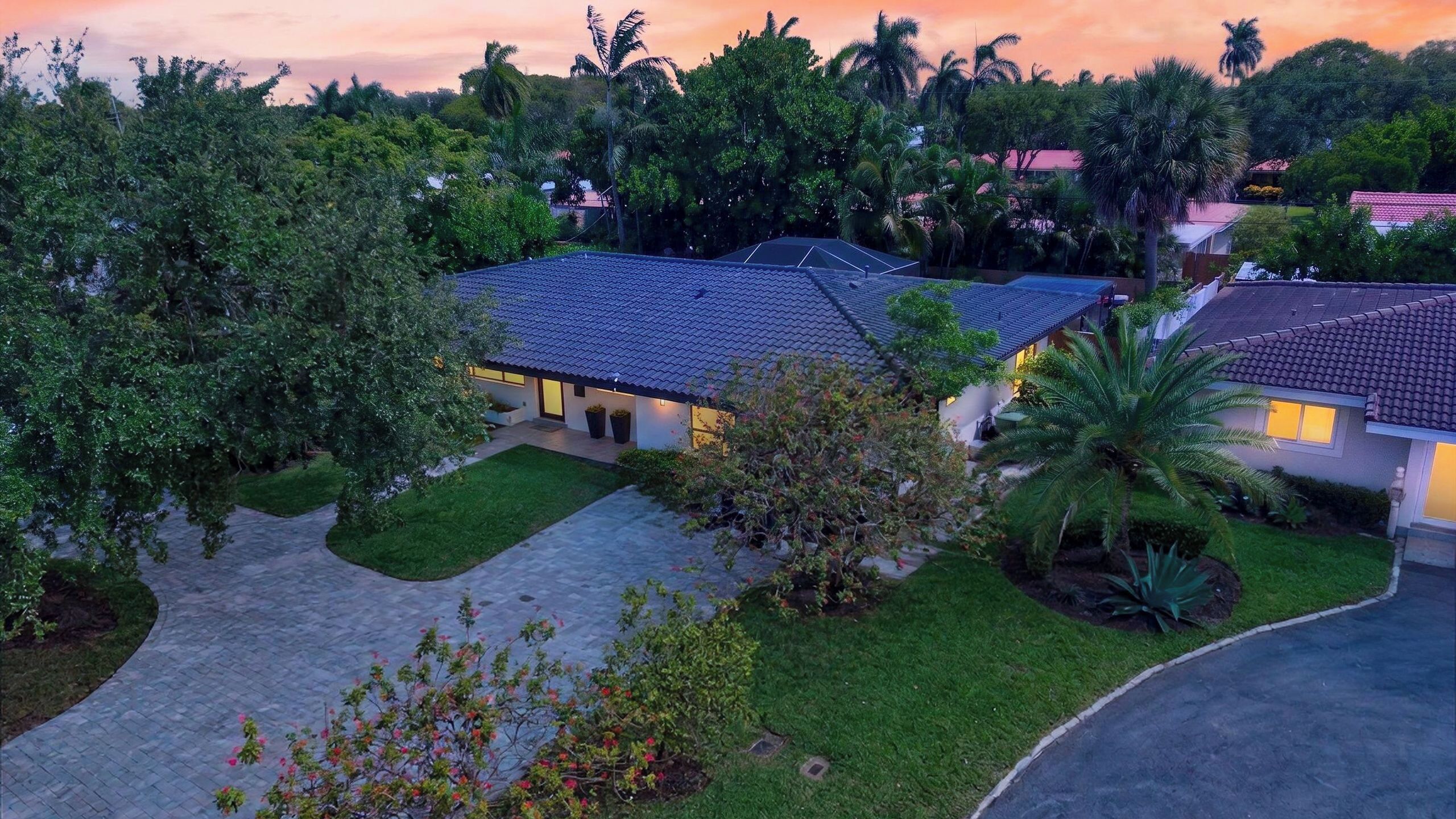 A residential area with houses, a paved driveway, and surrounding greenery.