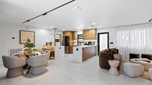 A modern living room with a dining area, kitchen, and a large window with sheer curtains. - Soleil Oasis by Avantstay Screened Pool + Outdoor Lounge + Firepit Near the Beach (Fort Lauderdale)
