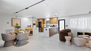 A modern living room with a dining area, kitchen, and a large window with sheer curtains. - Soleil Oasis by Avantstay Screened Pool + Outdoor Lounge + Firepit Near the Beach (Fort Lauderdale)