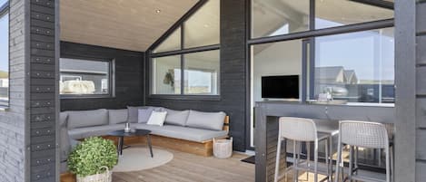 A modern outdoor seating area with a sofa, chairs, and a television.